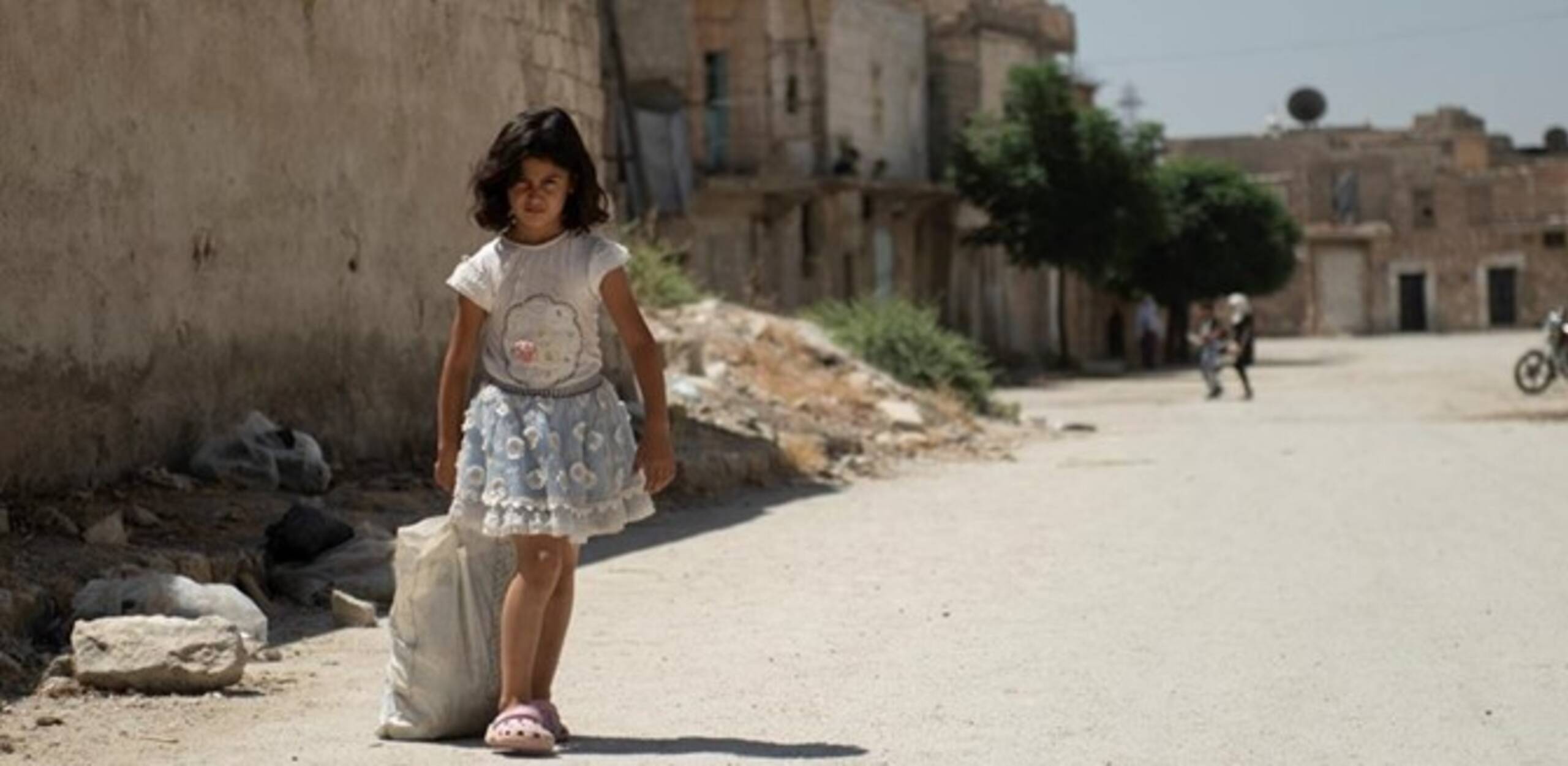A Syrian girl on her way through the destroyed streets of Aleppo - the project supports vulnerable families with life-saving aid.