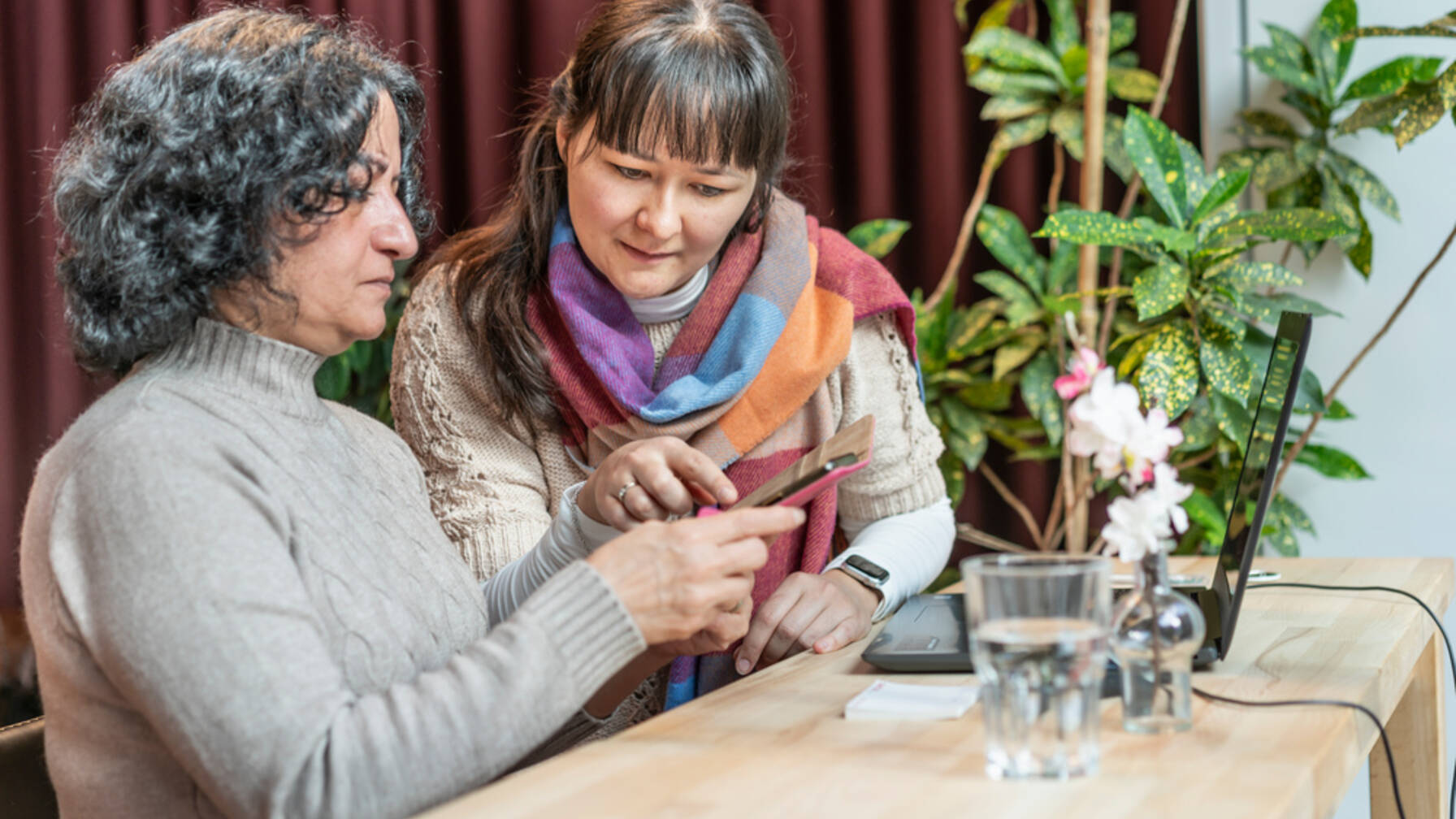 A volunteer helps people use smartphones and laptops as part of Caritas' «Digital Participation» project.