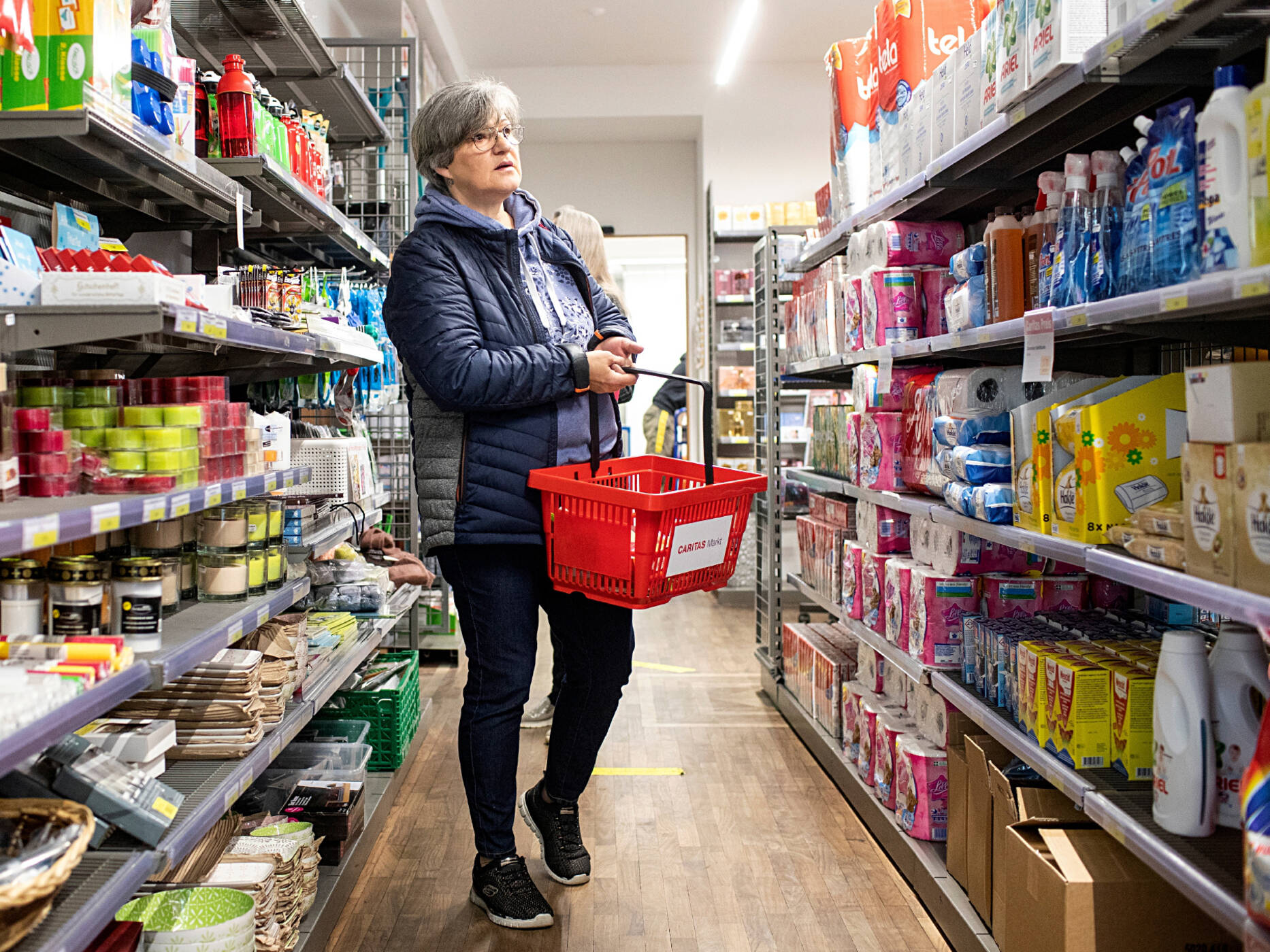 Une femme fait ses courses dans une Épicerie Caritas