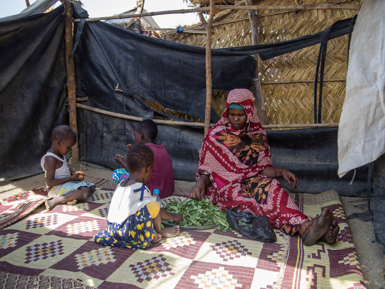Mariam gioca con i bambini all'ombra davanti alla sua capanna.