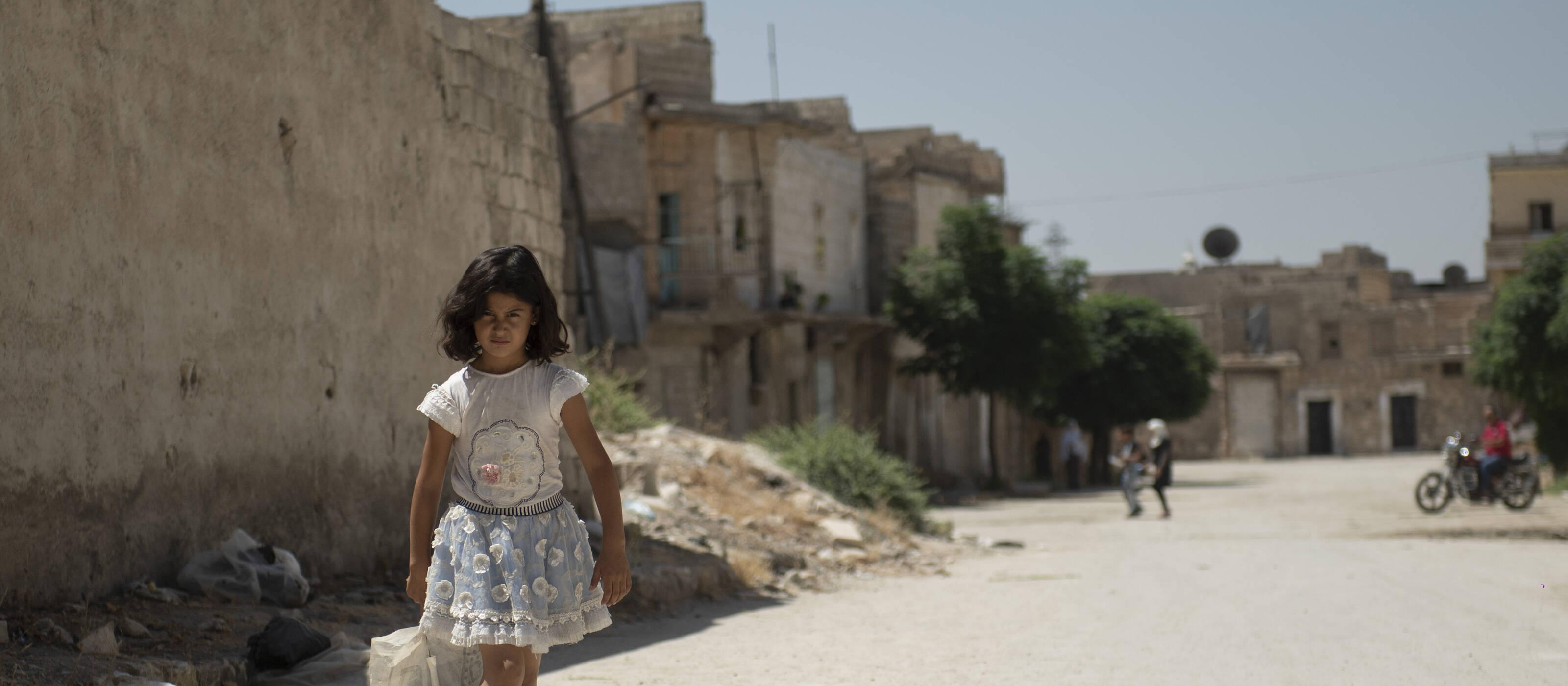 Ein syrisches Mädchen auf dem Weg durch die zerstörten Strassen Aleppos – durch das Projekt werden gefährdete Familien mit lebensrettender Hilfe unterstützt.