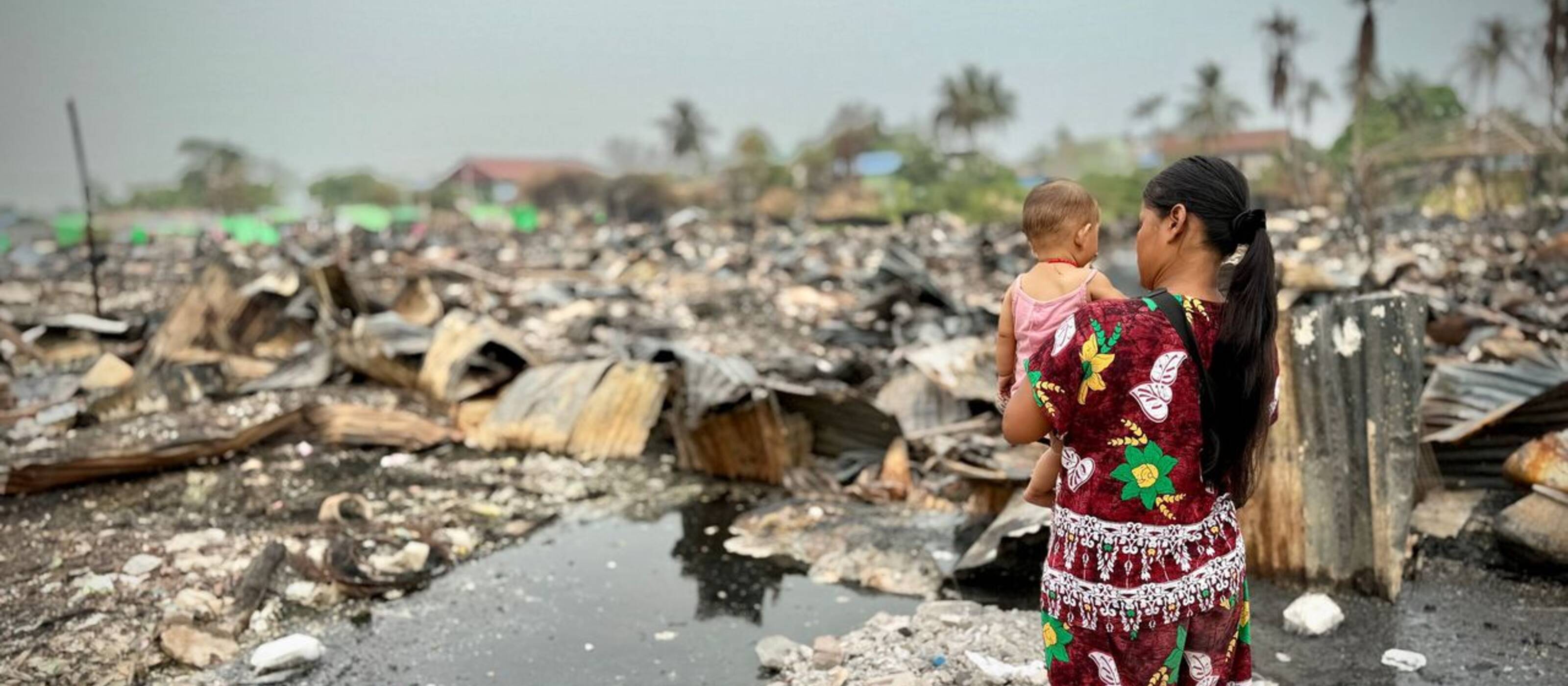 Dwa Kalaya* et sa fille de sept mois devant leur maison détruite.
