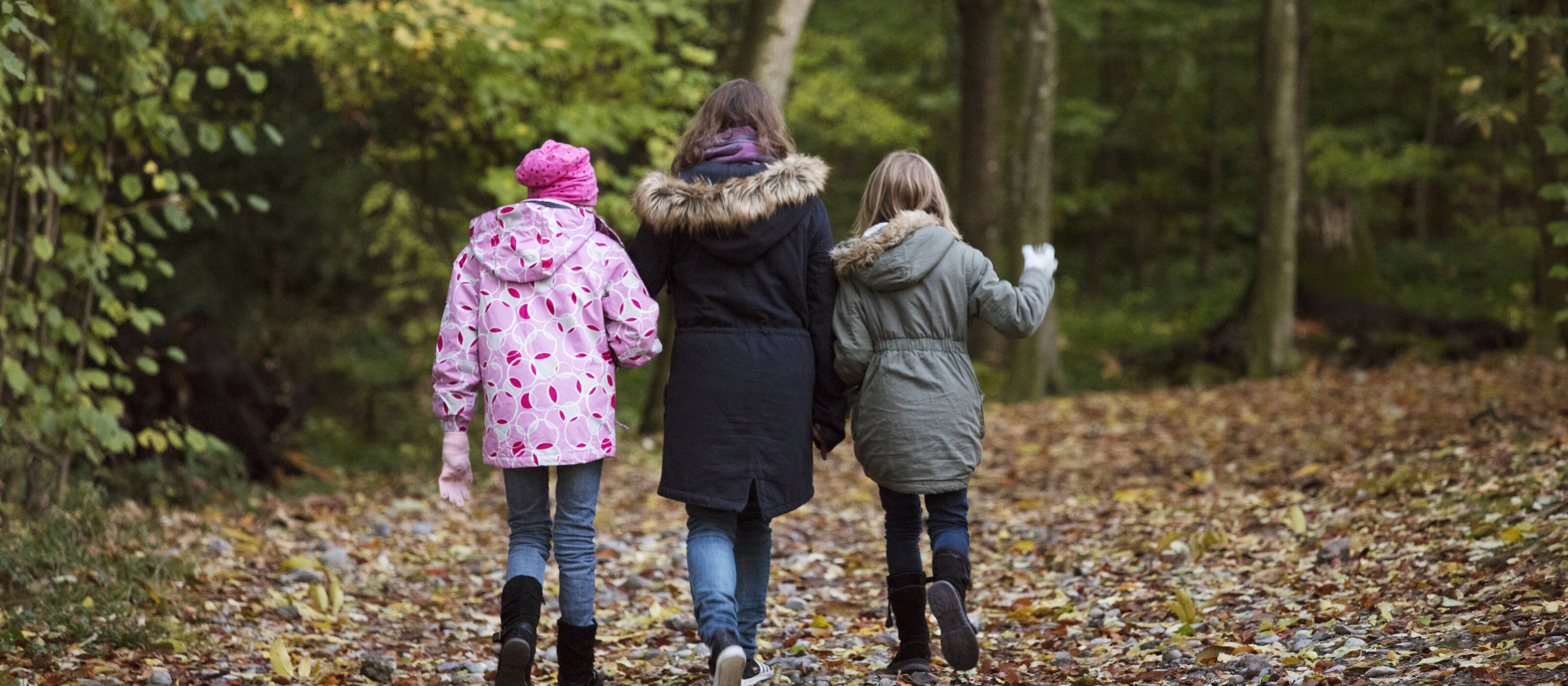 Una madre corre con i suoi due figli attraverso il bosco