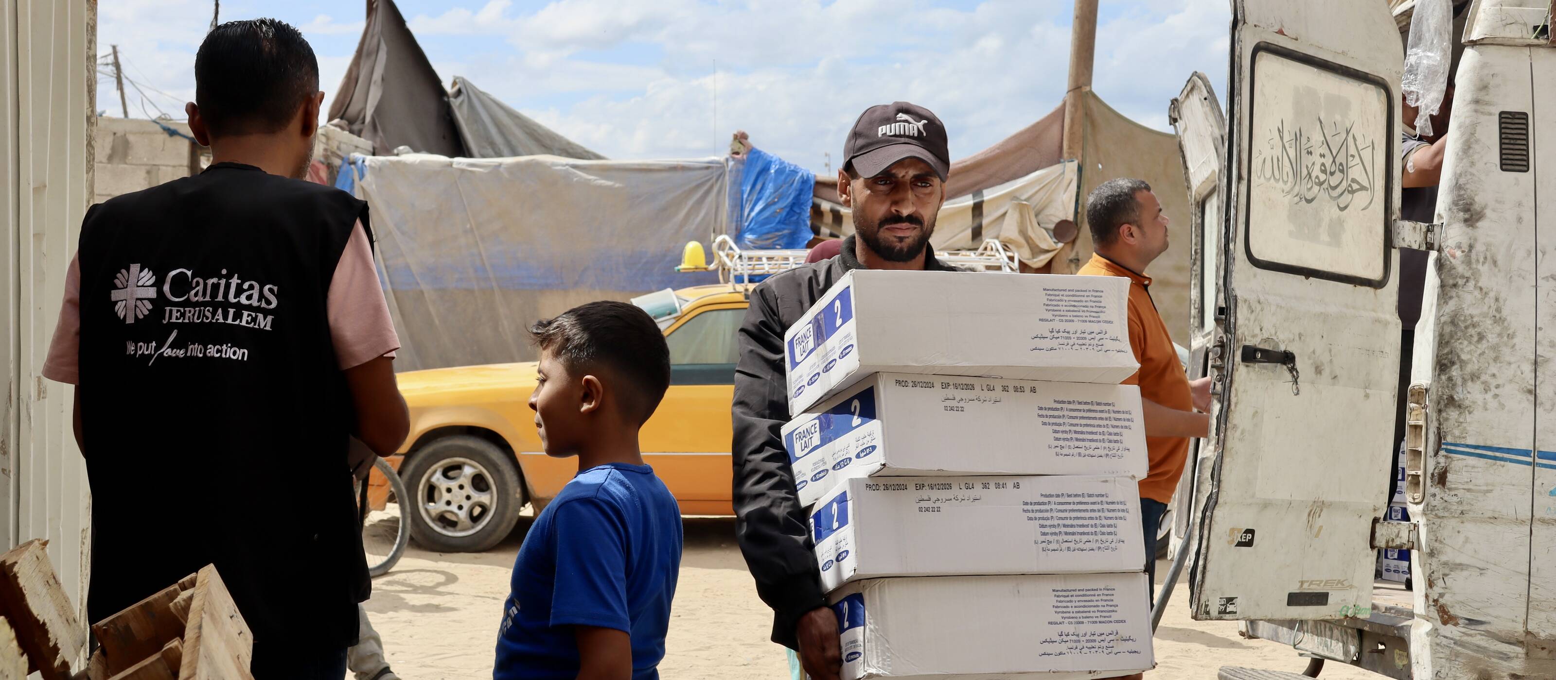 Deux hommes et un enfant dans un camp de la bande de Gaza avec des aliments pour bébés.