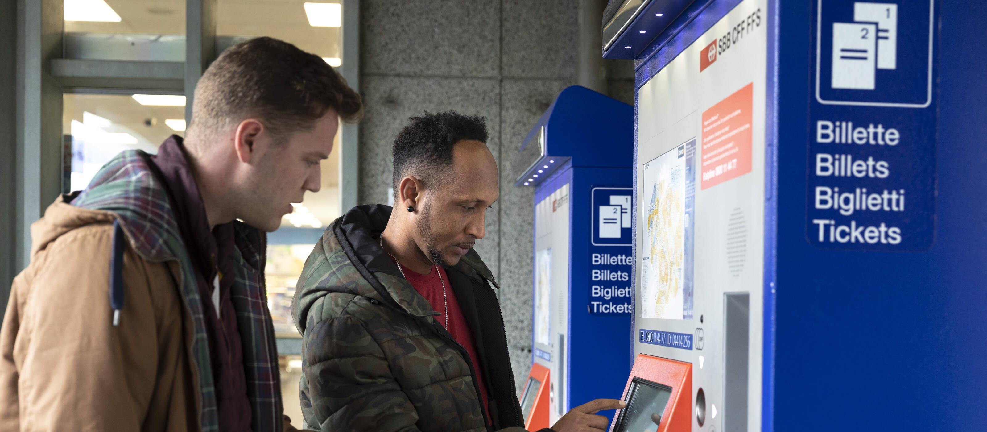 Zwei Männer lösen ein Bahnticket.