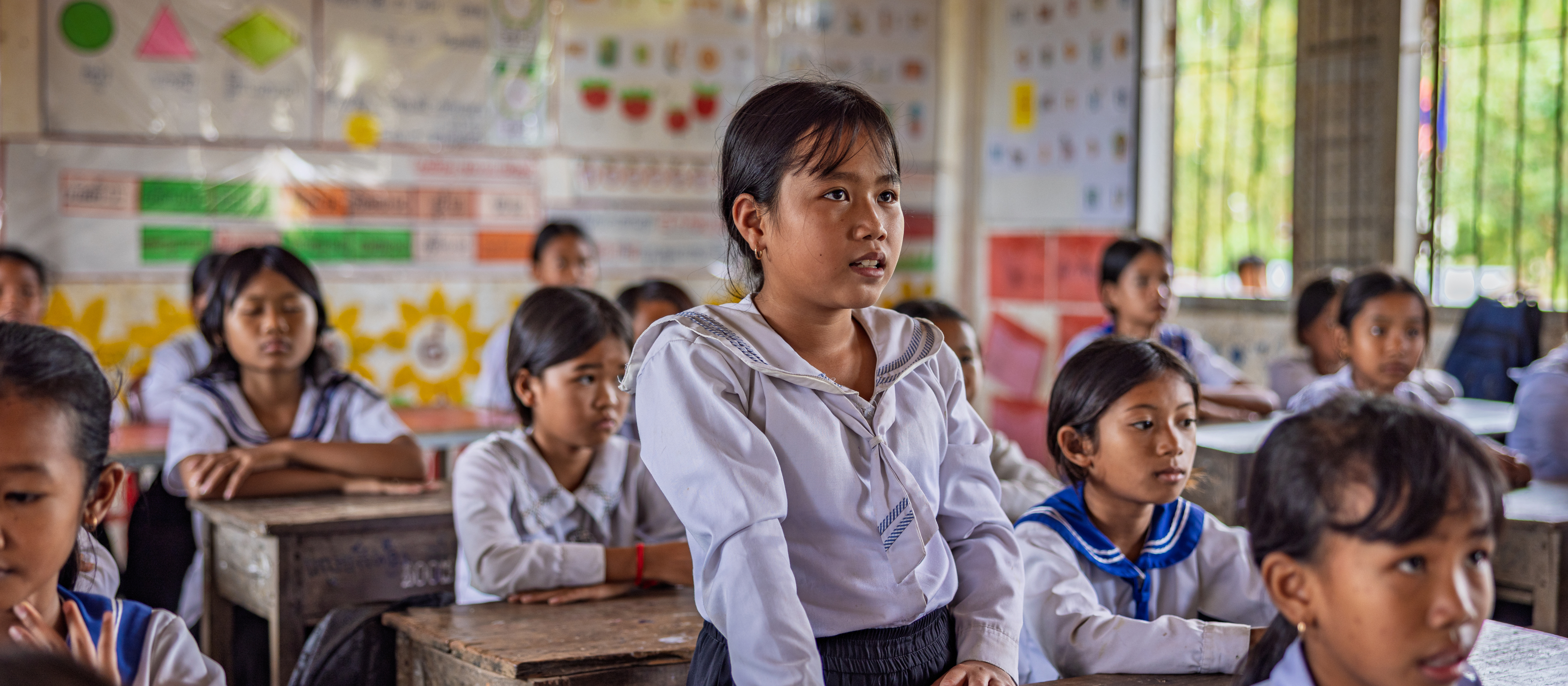 Nary und ihre Schulkolleginnen und Kollegen lauschen der Lehrerin und eignen sich Wissen über Umweltschutz an. Sie besuchen eine Blue School im Nordwesten Kambodschas.