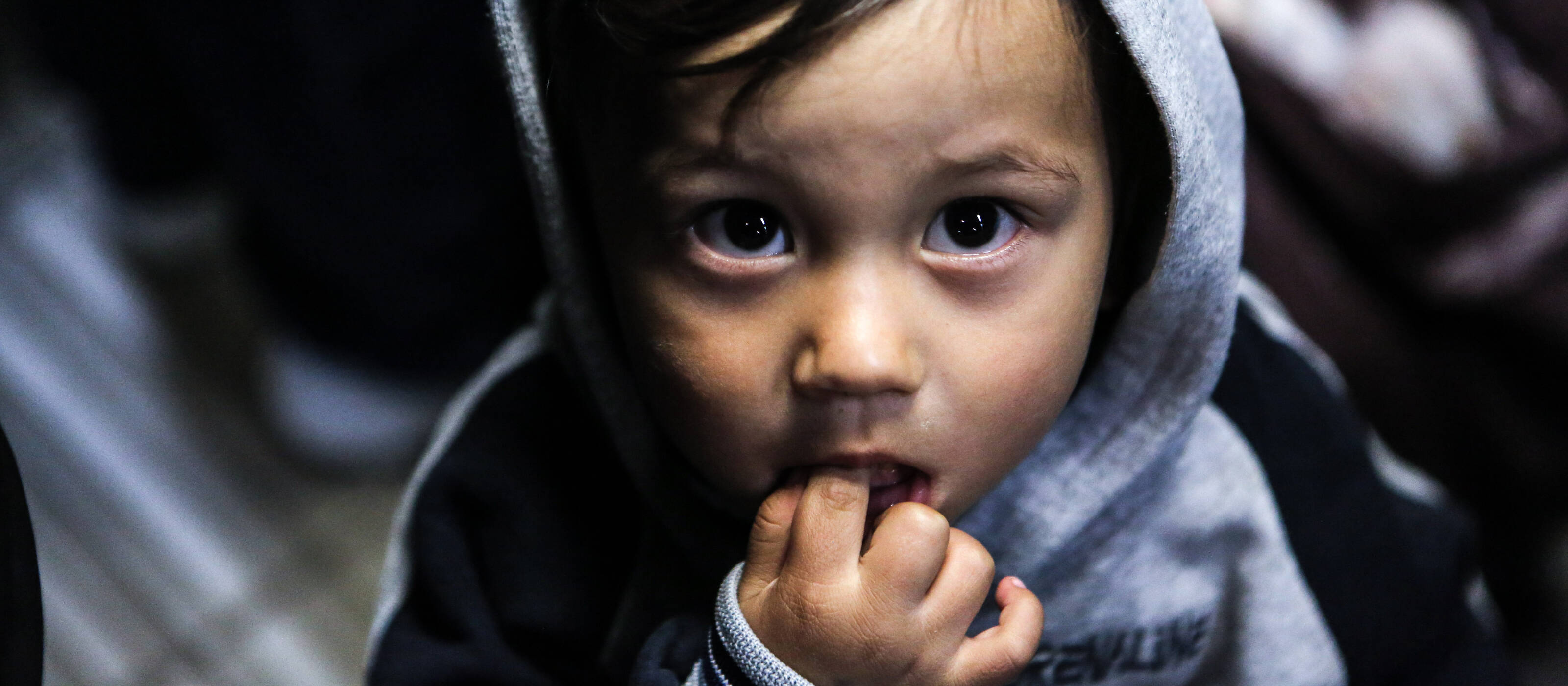A little boy looks into the camera with wide eyes.
