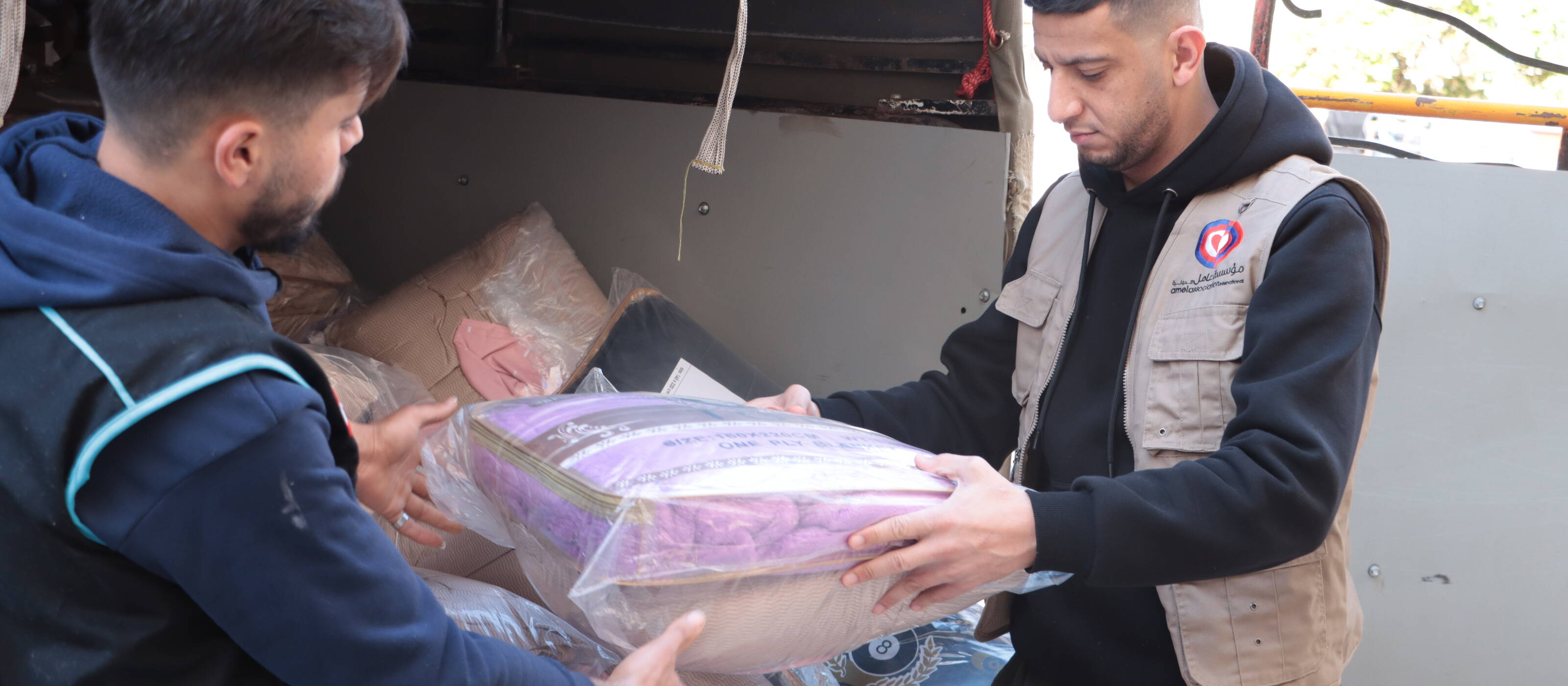 Un collaboratore dell’organizzazione partner di Caritas, Amel, distribuisce coperte ai profughi provenienti dal sud del Libano. 