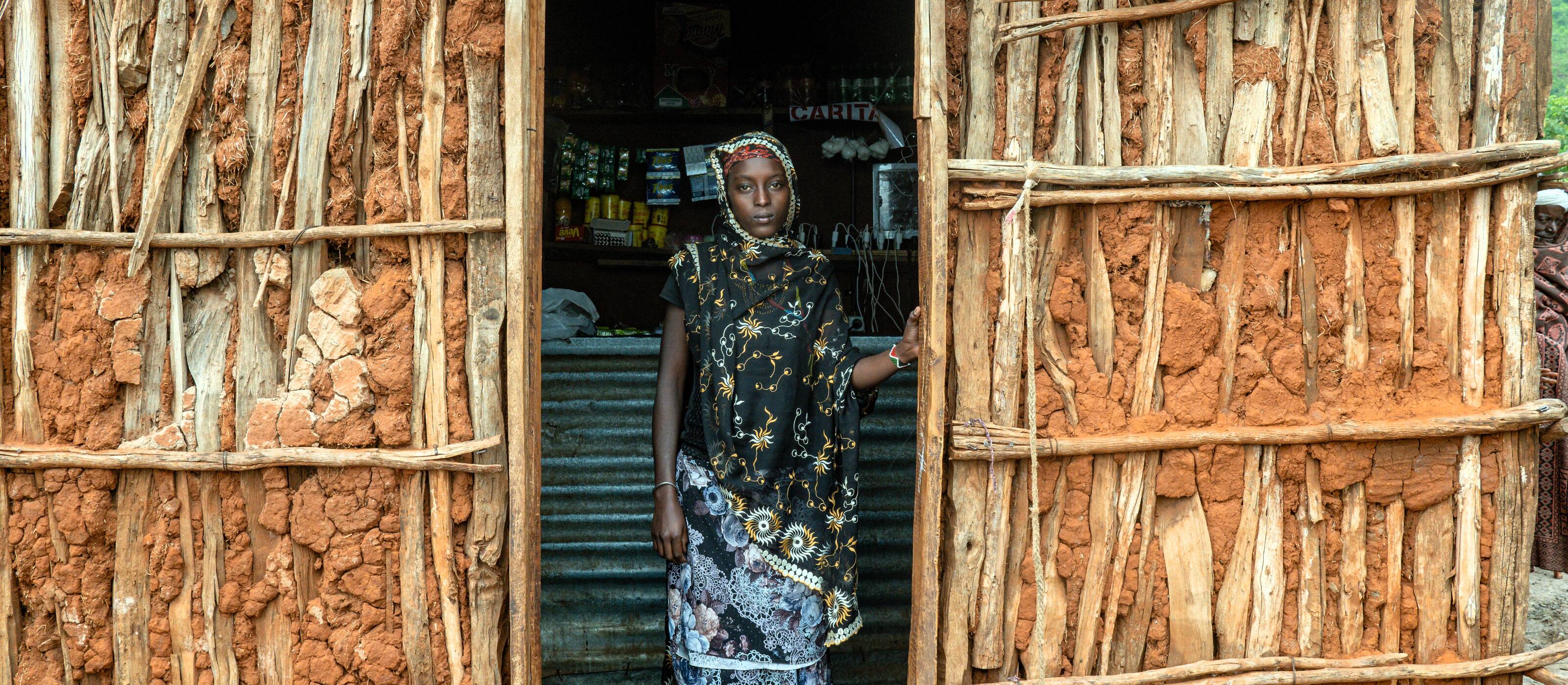 Une jeune femme regarde par la fenêtre de son immeuble.