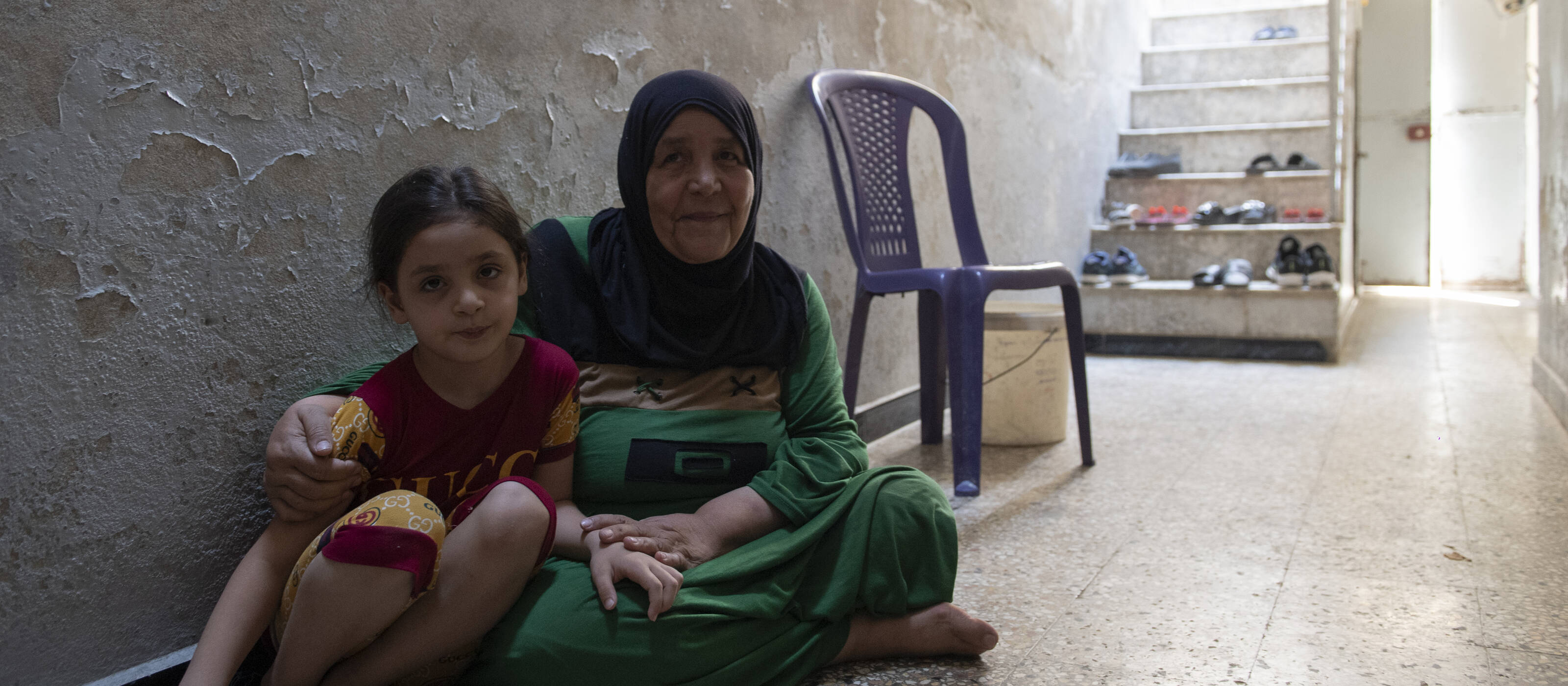 A woman and her daughter are sitting on the floor.