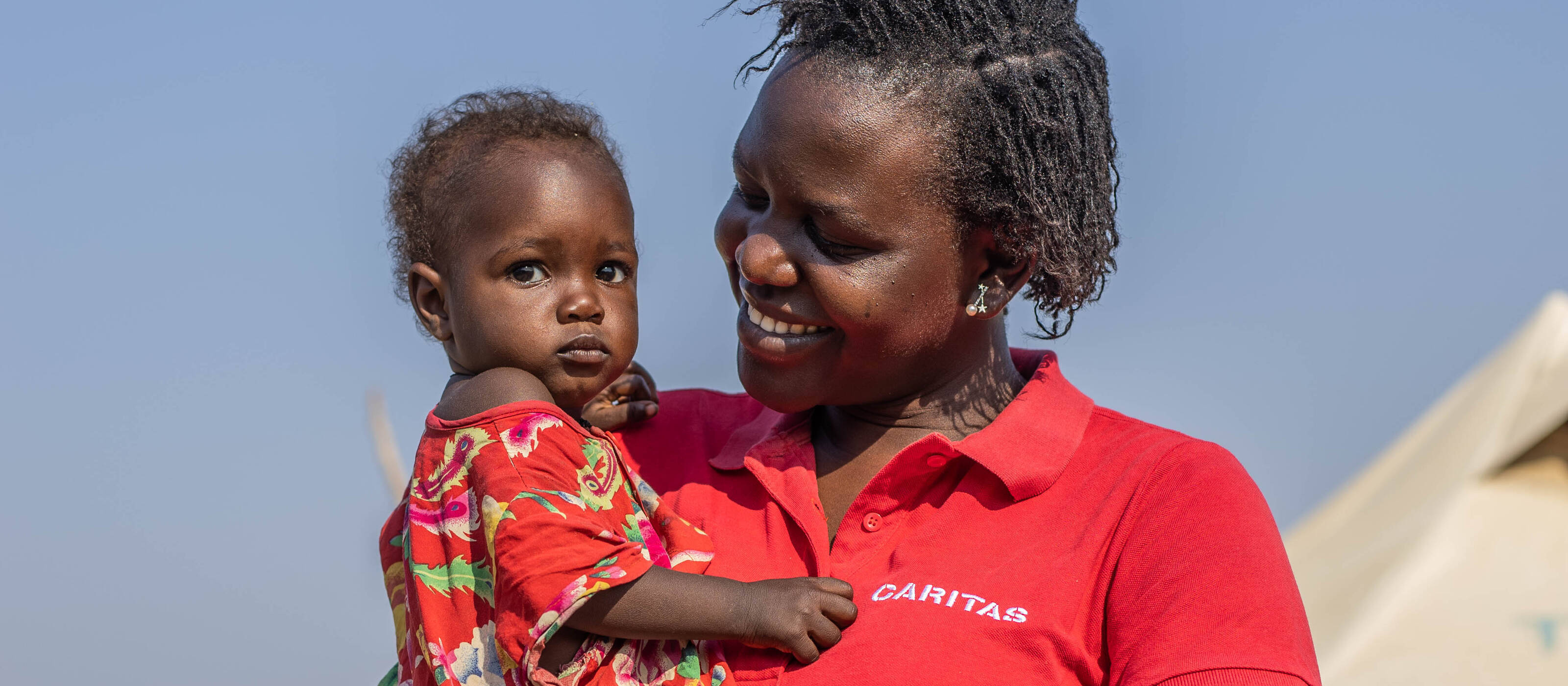 Jenifa Jopute, Projektmitarbeiterin im Südsudan, mit einem Kind auf dem arm