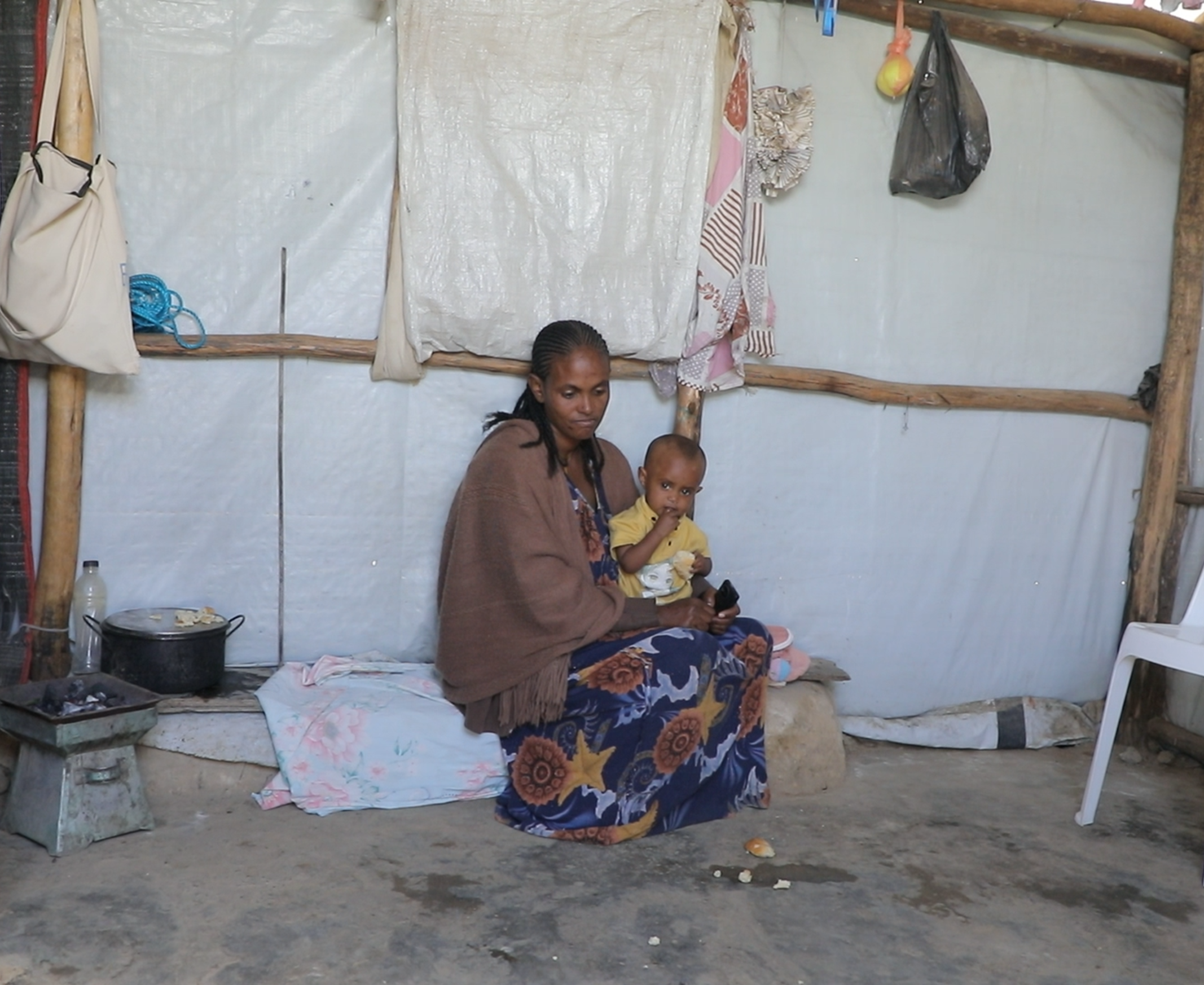Eine Frau mit Kind sitzt am Boden in ihrem sporadisch eingerichteten Zelt in einem Lager in Tigray, im Norden Äthiopiens.