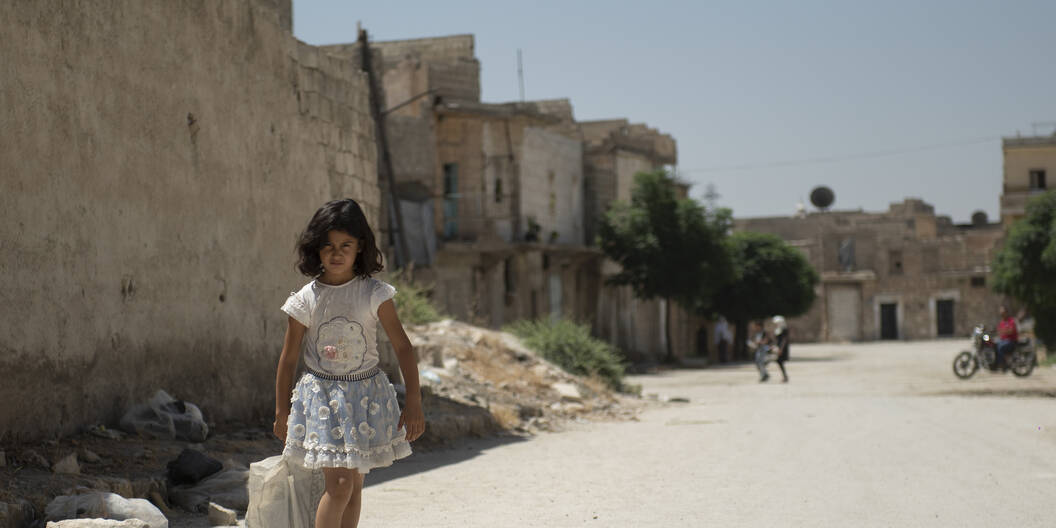 Ein syrisches Mädchen auf dem Weg durch die zerstörten Strassen Aleppos – durch das Projekt werden gefährdete Familien mit lebensrettender Hilfe unterstützt.