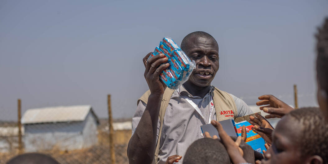 Ein Mann verteilt Crackers an Kinder.