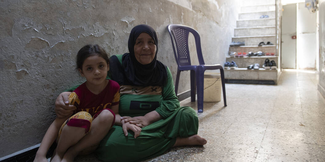 Une femme et sa fille sont assises par terre.