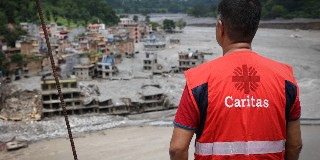 Mitarbeiter von Caritas Nepal blickt auf das zerstörte Gebiet